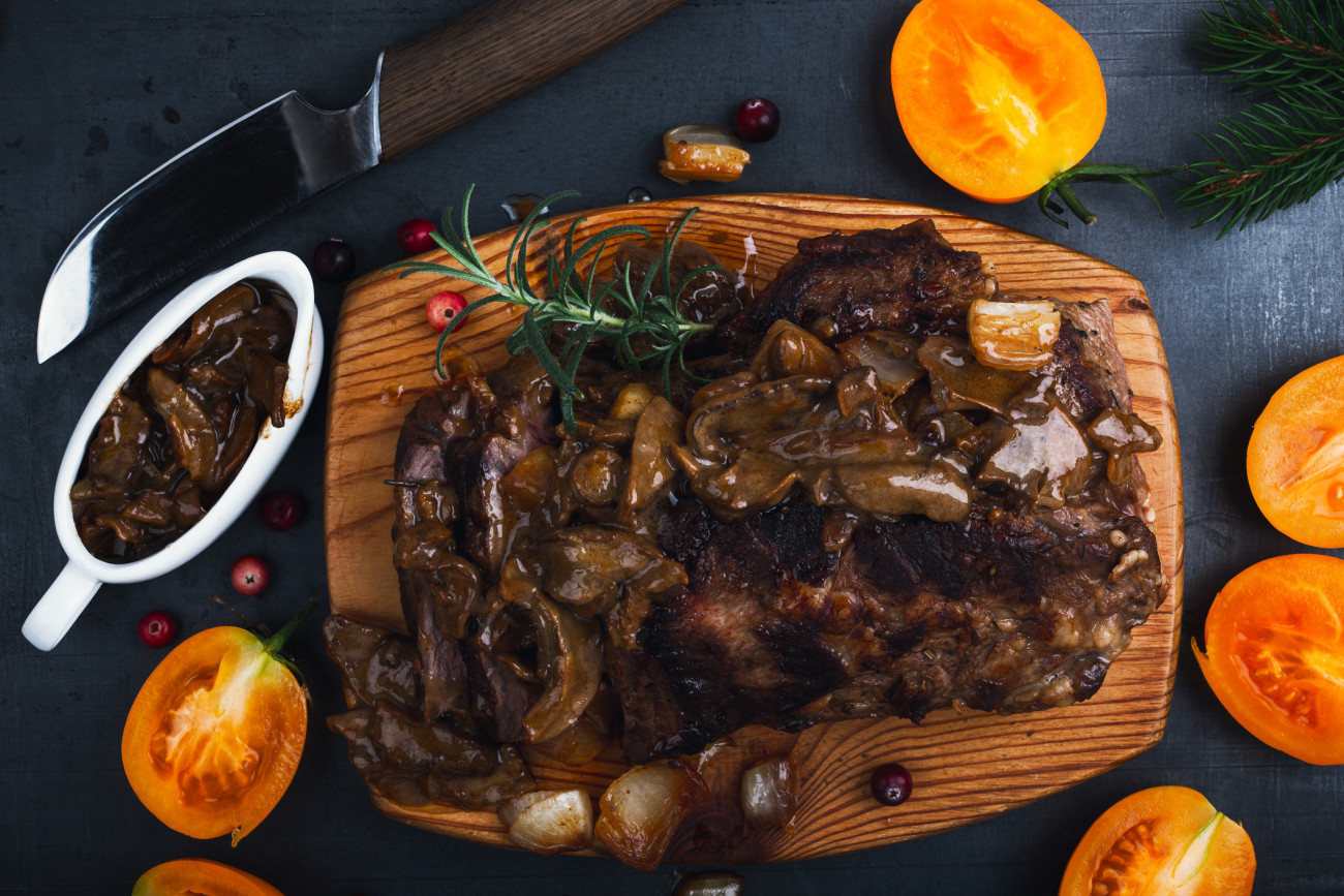 Roasted veal steak on board served with mushroom sauce viewed from above, Christmas dinner