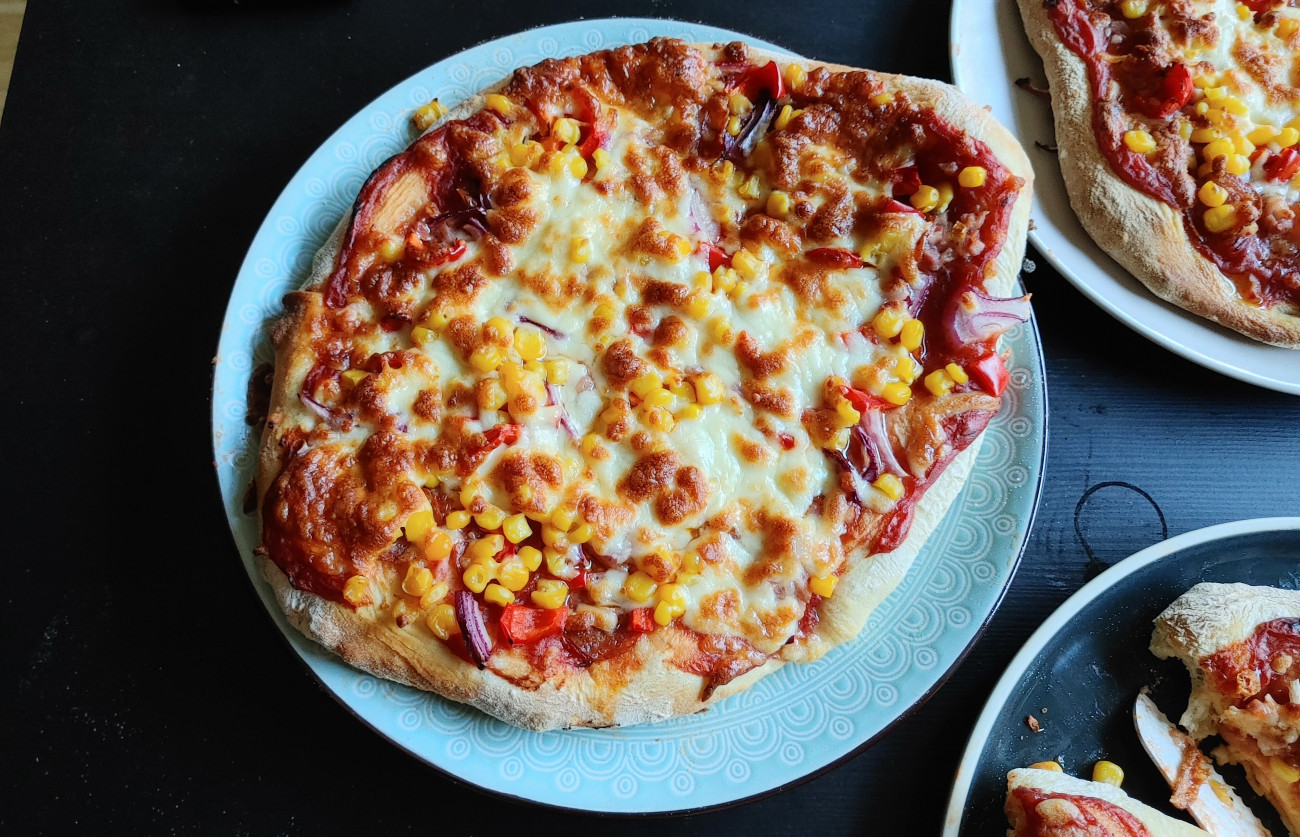 Házi pizza (paradicsomos alap, kolbász, bacon, lila hagyma, kukorica, sajt)